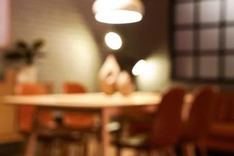 Blurred view of modern dining room with glowing lamps and table Stock Photos
