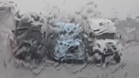 Blurred view of parked trucks through a rain-soaked windshield Stock Footage 281764127