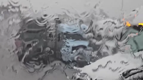 Blurred view of parked trucks through a rain-soaked windshield Stock Footage 281764159