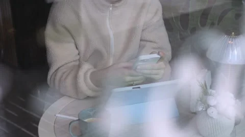Blurred view of person using devices near coffee cup and lamp Stock Footage 342076092