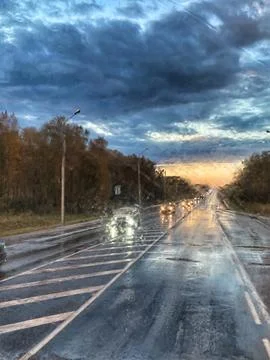 Blurred view of the road through the windshield of a car with rain. Raindrops on Stock-Fotos