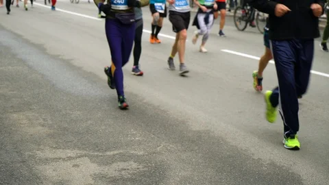 Blurred view of runners legs running marathon on asphalt road in city Stock Footage 106489794