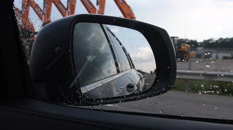 Blurred view in side mirror of fast moving car in rainy weather Stock Photos