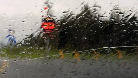 Blurred view through a rain-splattered car windshield looking at a wet country Stock Photos