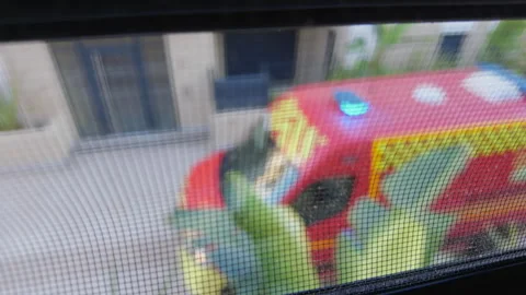 Blurred view through a window screen of a red emergency vehicle parked below, Stock Footage 344819700