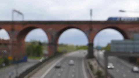 Blurred view of train on viaduct and highway traffic below Vídeos de archivo 189791476