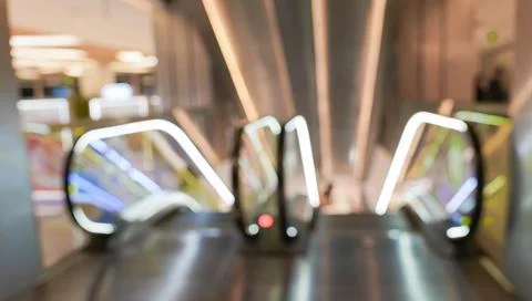 Blurred view of two escalators leading up through a modern shopping mall. Stock Photos