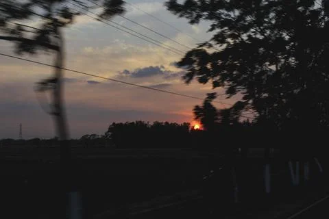Blurred view of a vibrant sunset over dark rural landscape and power lines Stock Photos