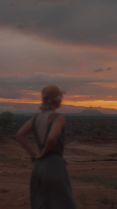 Blurred view of young blonde in cap against backdrop of mountains at sunset and Video stock 316812727