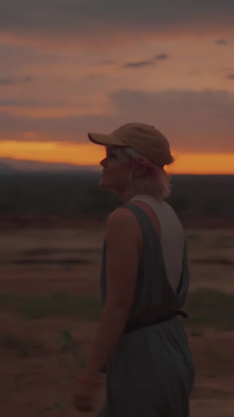 Blurred view of young blonde in cap against backdrop of mountains at sunset and Video stock 317039413