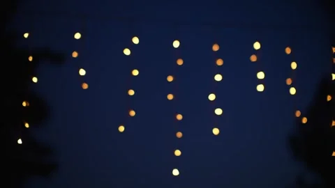 Blurred warm string lights glow as golden bokeh against blue night background Stock Footage 342299170