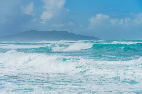 Blurred waves on the beach with a mountain backdrop, serene and picturesque Stock Photos
