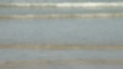 Blurred waves gently rolling onto a sandy beach Stock Footage