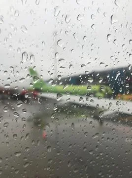 The blurred wing of the plane is visible through a drop of rain on the window Stock Photos