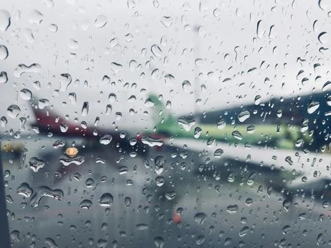 The blurred wing of the plane is visible through a drop of rain on the window Stock Photos