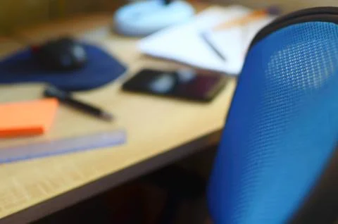 Blurred work office with a small focus on desk chair and a black cell phone. Stock Photos