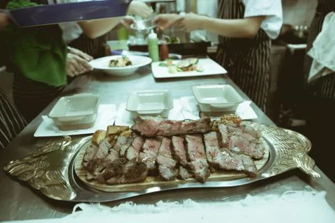 Blurry background of Beef on silver tray and chef in hotel or restaurant kitc Stock Photos