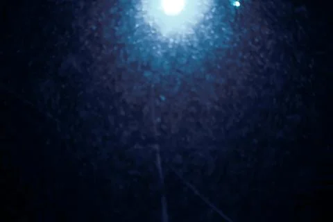 Blurry background with falling soft snow flake under glowing lantern at nig.. Stock Photos
