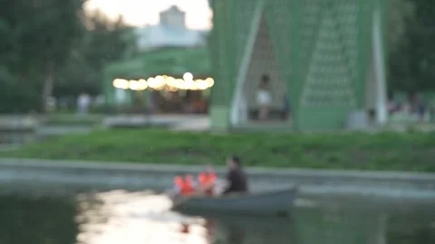 Blurry bokeh background of people rowing boat in park pond. Stock Footage 341135829