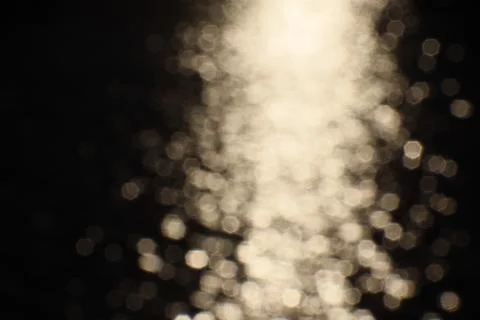 Blurry bokeh of sunset reflection in surface of lake as background Stock Photos