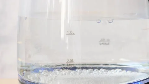 Blurry bubbles in hot water boiling inside glass teapot . Close-up of boiling wa Stock Footage 282654733