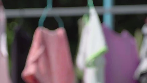 Blurry Clothes drying in the little wind on a clothesline outside in the sun Video stock 82395193