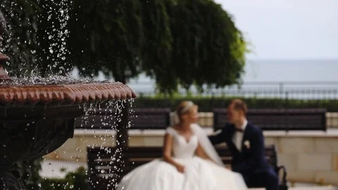 Blurry couple on bench and close fountain against building Stock Footage 113078668