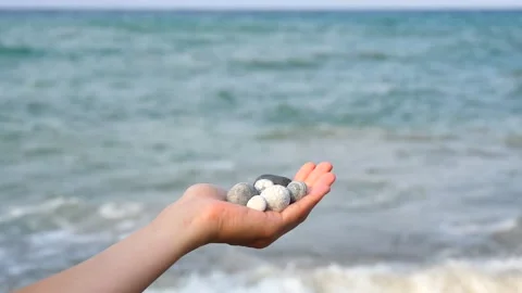 Blurry defocus Beautiful round gray and white sea stones lie in a female hand 库存影片 134745056