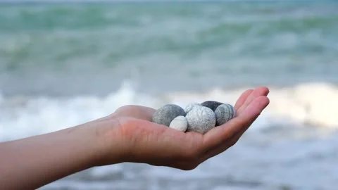 Blurry defocus Beautiful round gray and white sea stones lie in a female hand Stock Footage 134794641