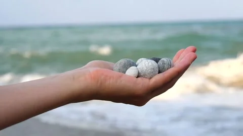 Blurry defocus Beautiful round gray and white sea stones lie in a female hand 库存影片 134796511