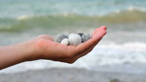 Blurry defocus Beautiful round gray and white sea stones lie in a female hand 库存影片 134796988