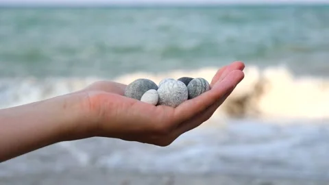 Blurry defocus Beautiful round gray and white sea stones lie in a female hand Stock Footage 134799592
