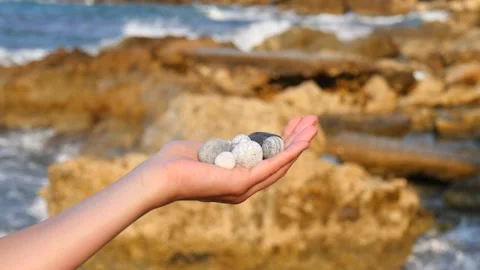 Blurry defocus Beautiful round gray and white sea stones lie in a female hand Stock Footage 134804623