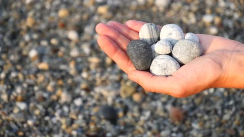 Blurry defocus Beautiful round gray, white sea stones lie in a female hand 库存影片 134812171