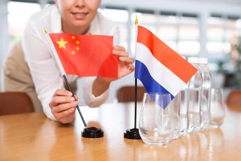Blurry girl set midget flags of Netherlands and China before international Stock Photos