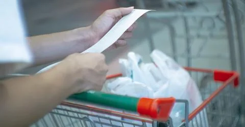 Blurry of hand of Asain man checking a bill with a long receipt in the supe.. Stock Photos