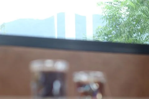 A blurry image of a cityscape viewed through a window, two drinks sit on a wo Stock Photos