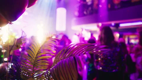 Blurry image of crowd at event with palm trees, balloons, and purple decoration Stock Footage 275157529