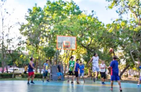 Blurry image of elderly men and teens playing basketball in the morning at Ba Stock Photos