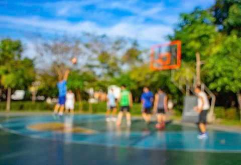 Blurry image of elderly men and teens playing basketball in the morning at Ba Stock Photos