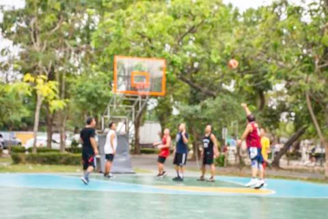 Blurry image of elderly men and teens playing basketball in the morning at Ba Stock-Fotos