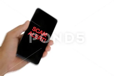 Blurry image of hand holding mobile phone with word SCAM ALERT. Stock Photos