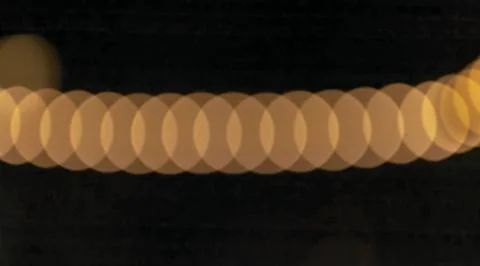 A blurry image of a long line of circles with a yellowish tint. overlapping.. Stock Photos