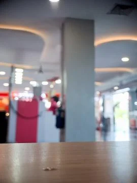 Blurry indoor mall background with empty wooden table in foreground. Stock Photos