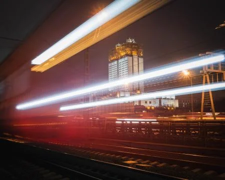 Blurry lights of a passing train. High building in the background. Stock Photos