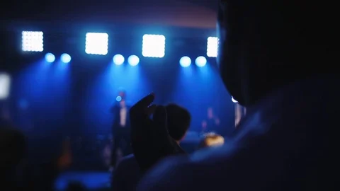 Blurry man claps against singer with microphone on stage Stock Footage 115521233
