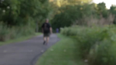 Blurry man walking away from camera on a nature trail wide shot 4k Stock Footage 215197613