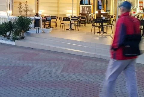 Blurry moving image of a man on the background of an empty street cafe, summer Foto stock