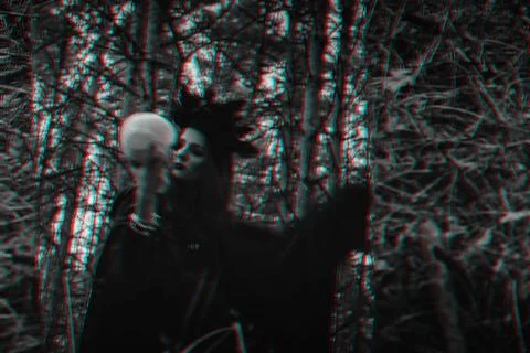 Blurry mystical reflection of a black witch with a skull in her hands performing Stock Photos