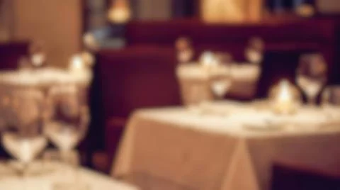 Blurry restaurant interior with elegant empty tables covered in white tablecl Stock Photos